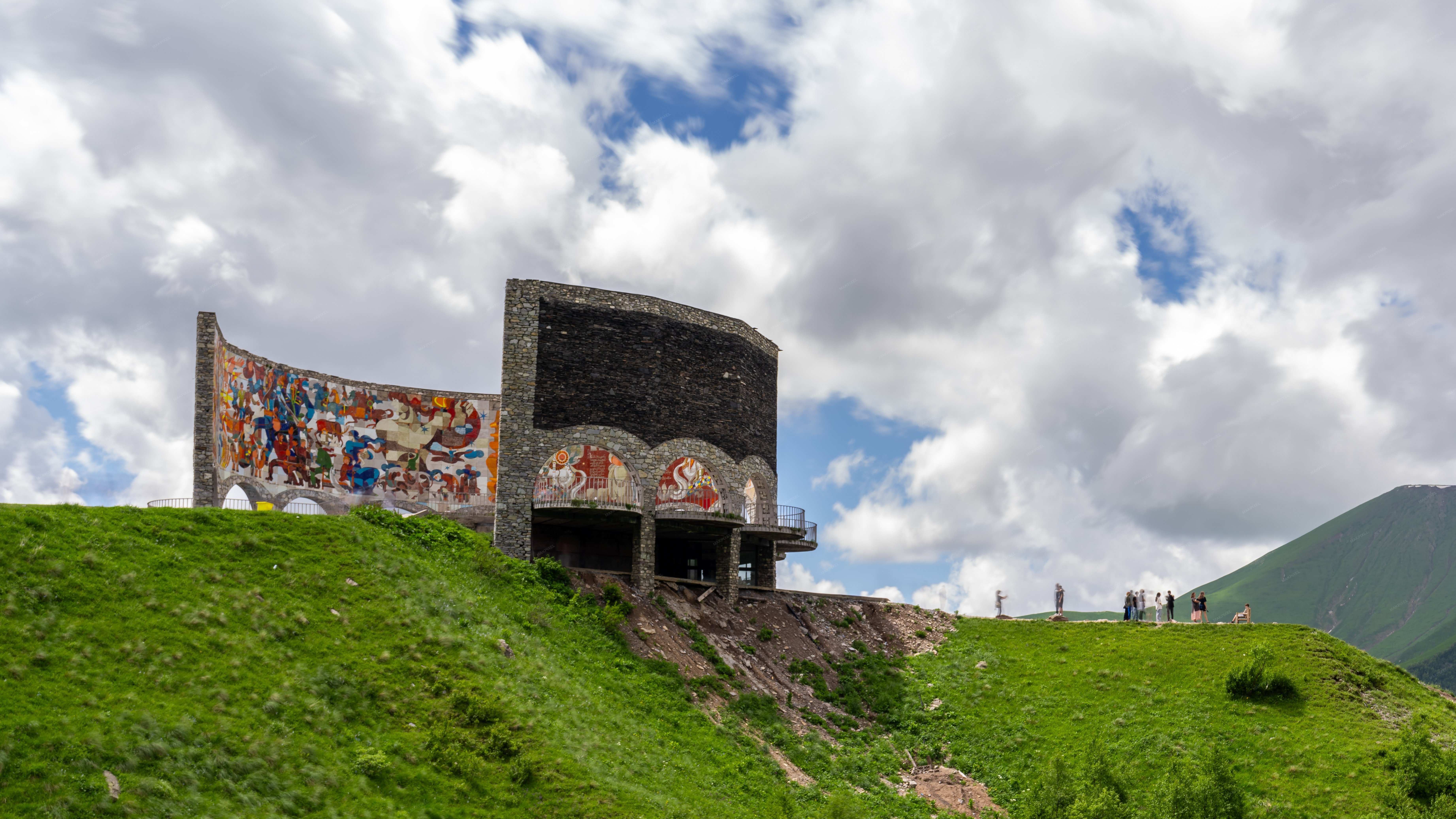large, colorful mural on a stone wall in the foreground, - Full size view
