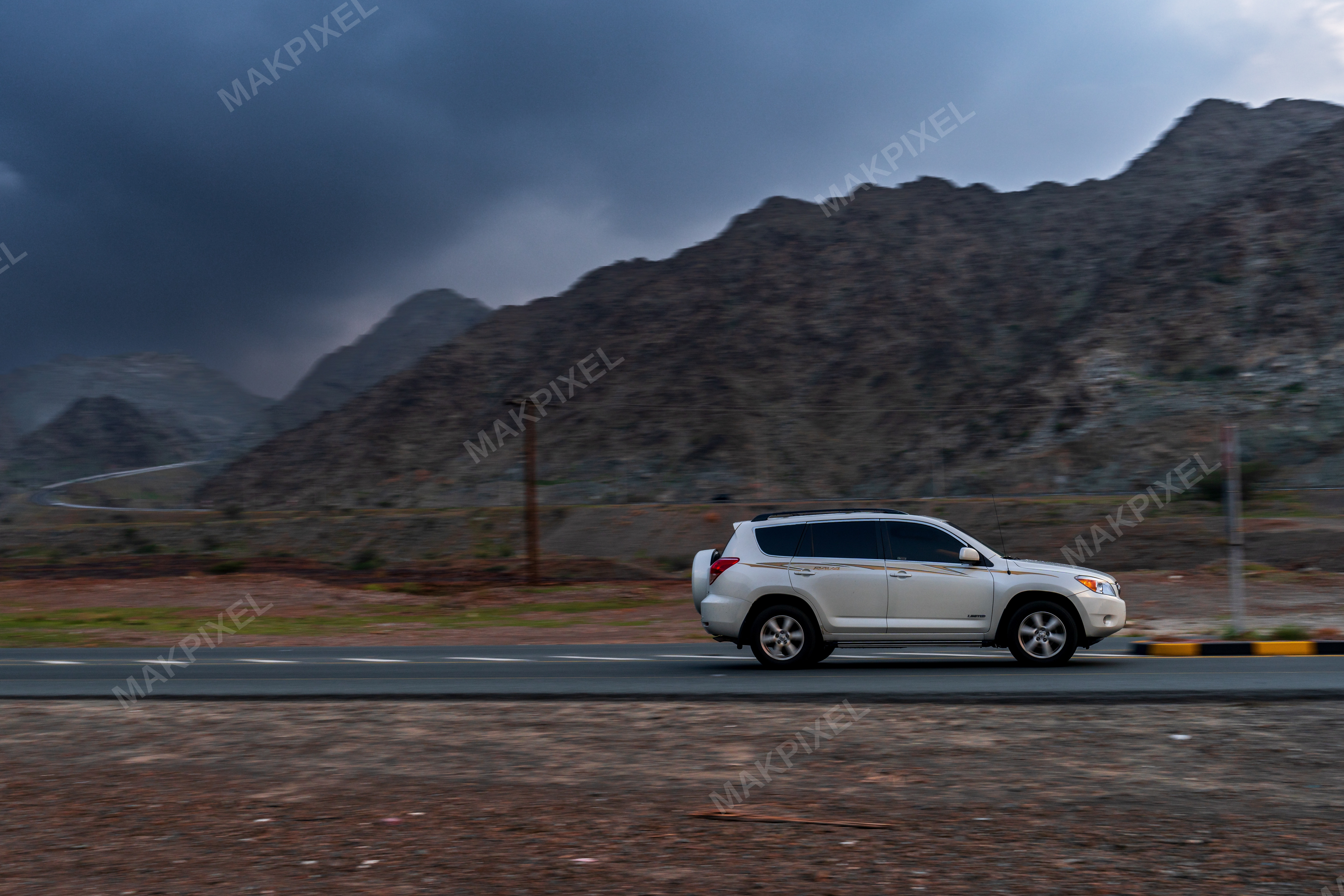 White SUV on Mountain Road, Masafi UAE – Scenic Landscape, Stormy Sky - Full size view