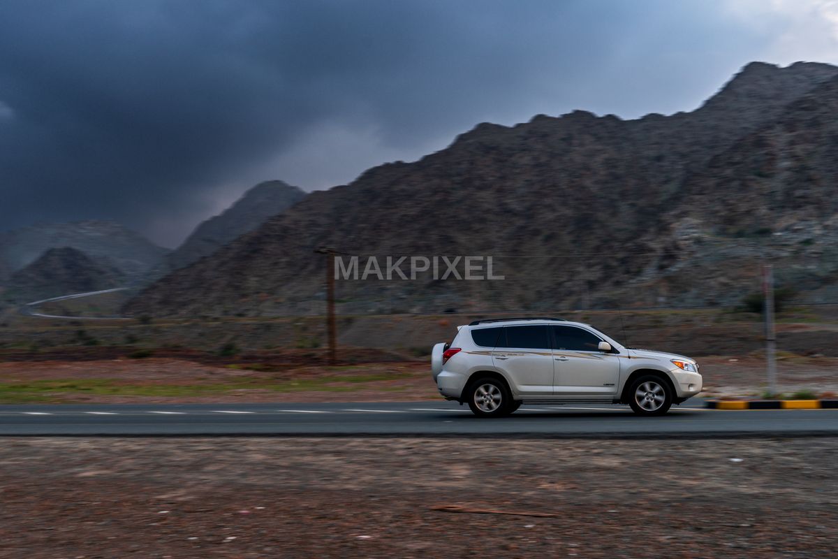 White SUV on Mountain Road, Masafi UAE – Scenic Landscape, Stormy Sky - 7787×5191 stock photo